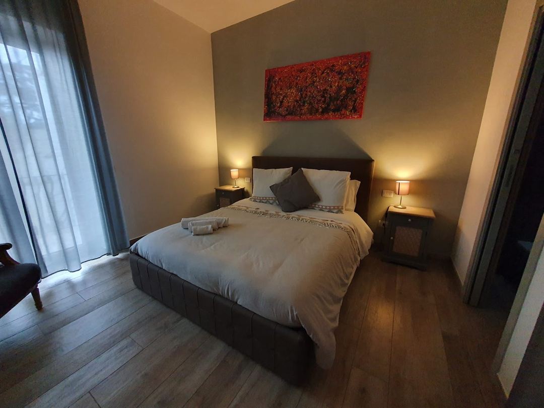 A modern bedroom at Villa Matilde B&B featuring a dark bed frame with white linens, bedside lamps, and warm ambient lighting.